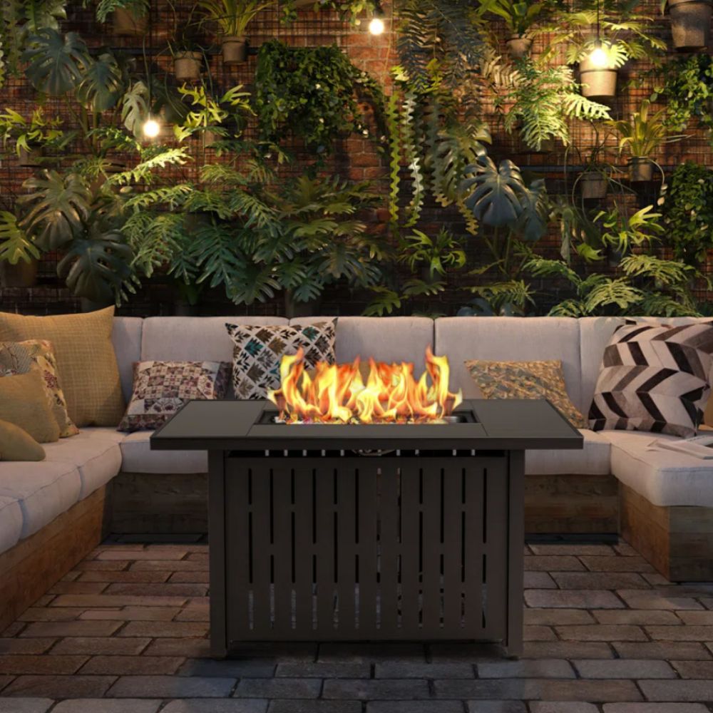 Firepit table in yard setting with outdoor sofa and living wall in the background