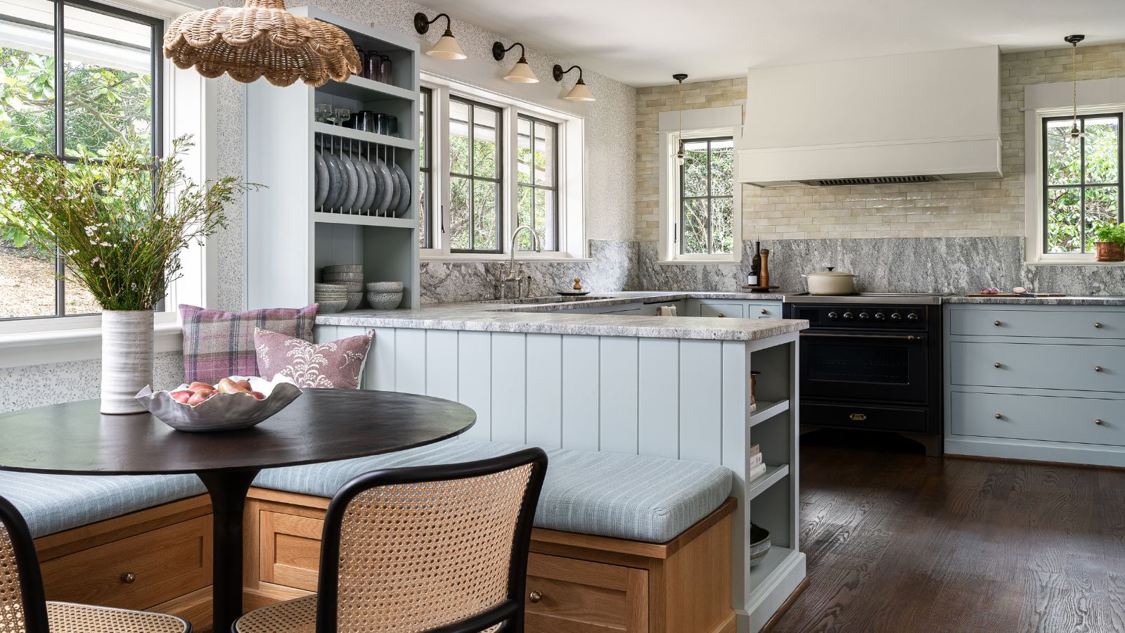 A kitchen with a peninsula island, a dining nook with banquette seating, and blue cabinets