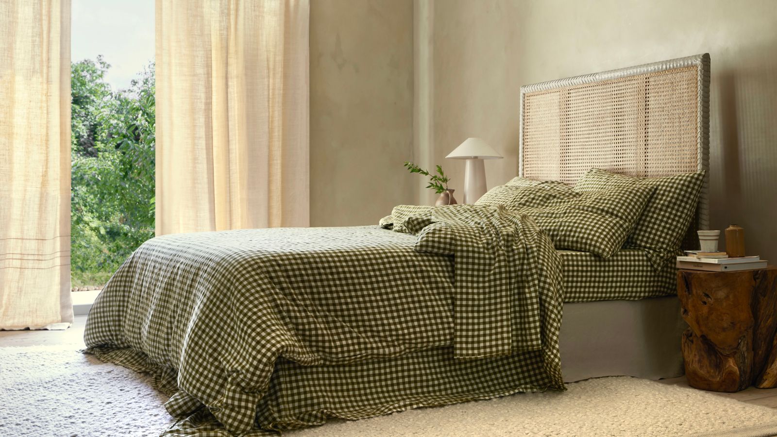 Side view of green gingham bedding on a bed against beige walls. 