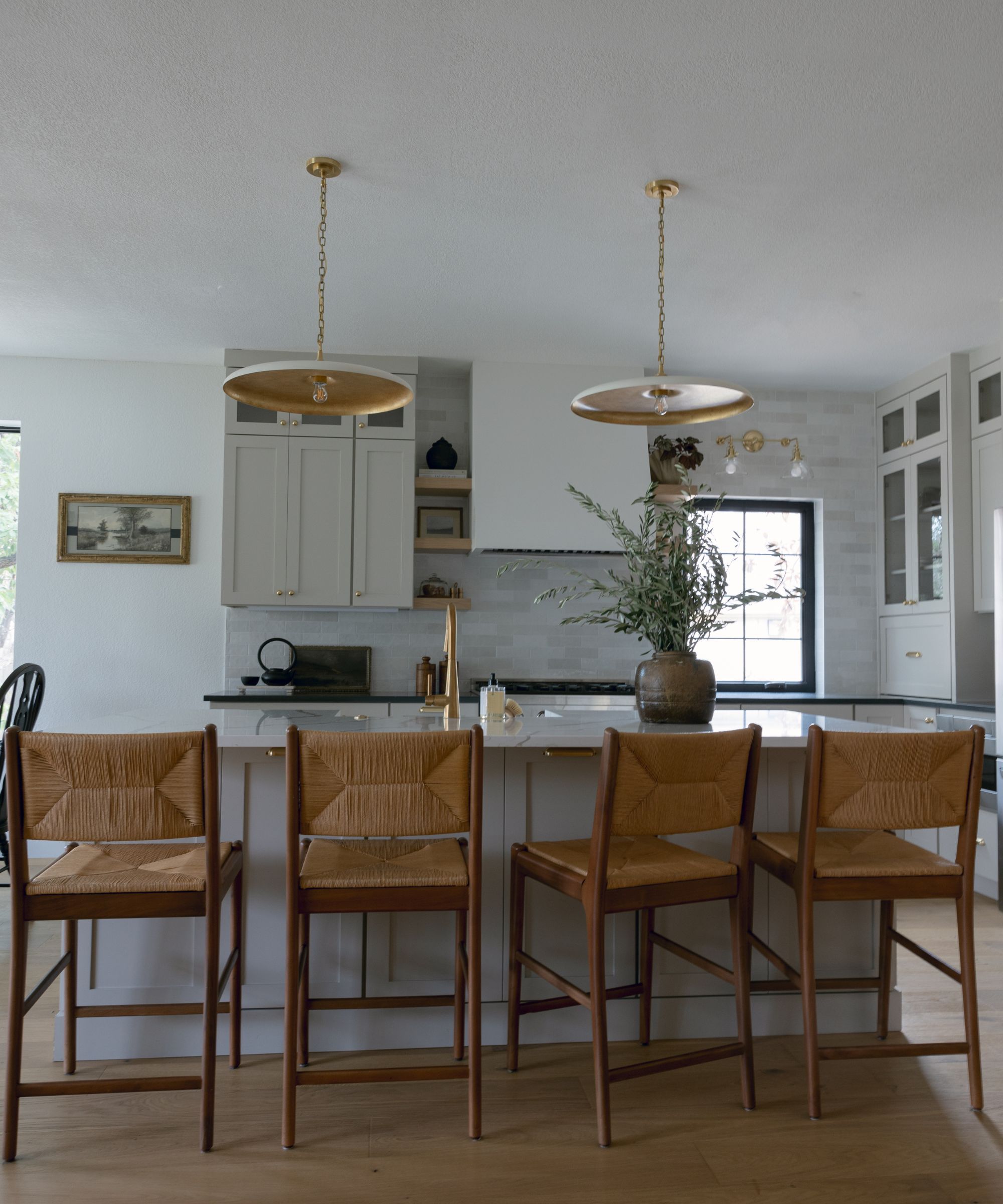 A modern kitchen with kitchen cabinets painted in Revere Pewter by Benjamin Moore, with kitchen bar stools against the kitchen island.