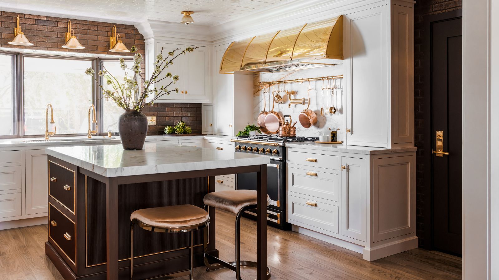 A white shaker kitchen with a brown island and gold accents